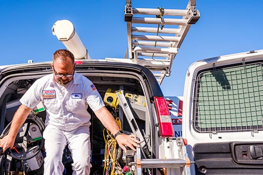 A George Brazil technician stepping out of a service van loaded with HVAC equipment